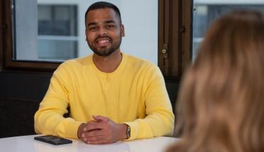 A young male ADHA employee sits at a table smiling for the camera.