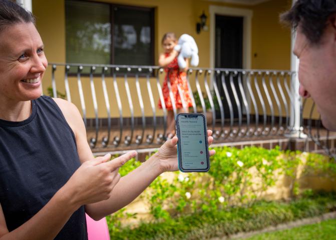 Woman showing mobile to man with My Health Record on screen