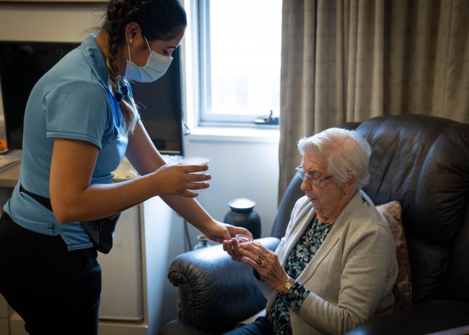Healthcare provider giving medication to an elderly person