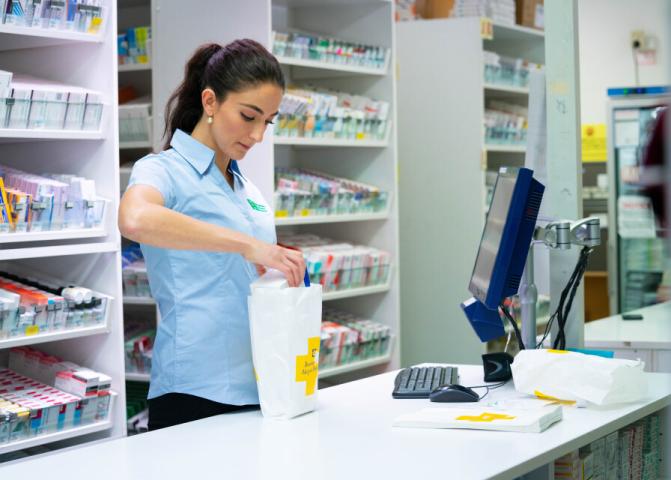 Pharmacist packaging medication behind counter