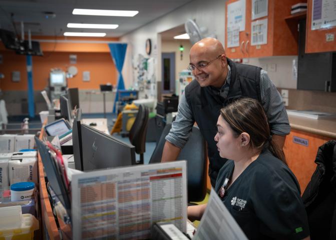 Two healthcare providers looking at a monitor screen in a hospital setting