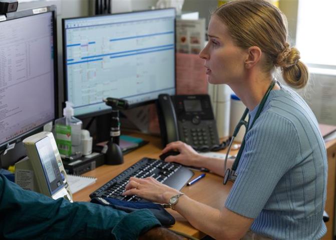General practioner sitting at desk looking at monitor