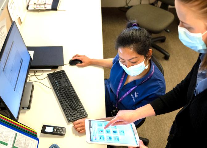 two healthcare workers using a tablet