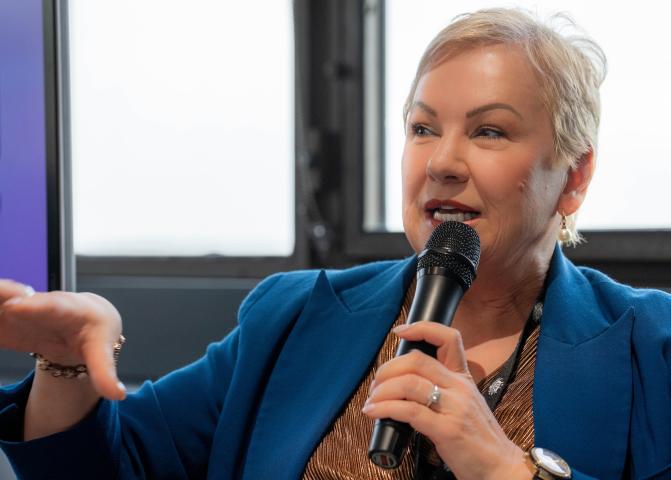 Lyn McGrath speaks on a microphone