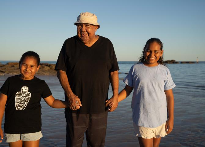 Image of three people holding hands walking on the beach