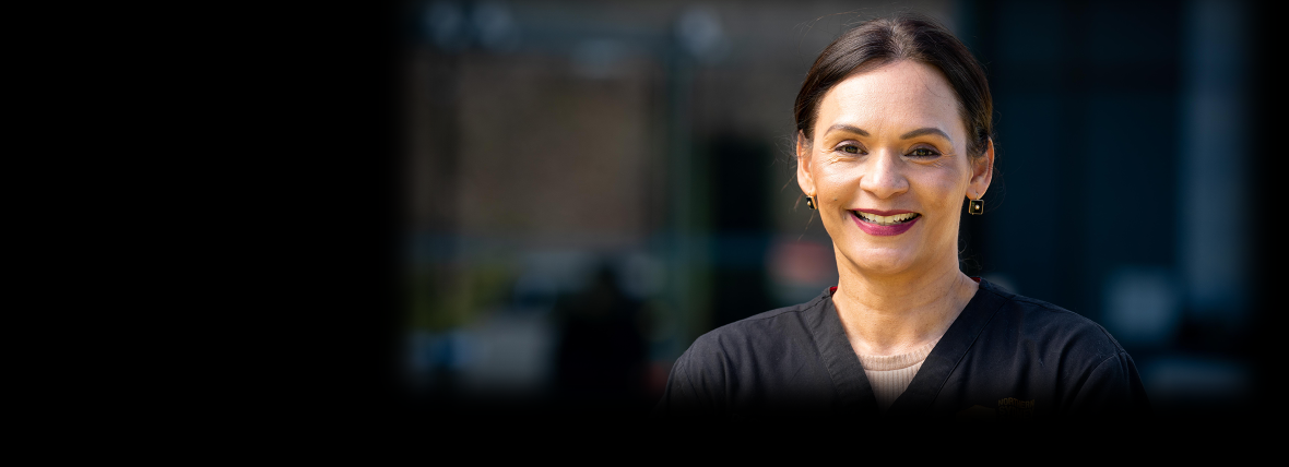 Digitally enabled outcome - Ensuring that health and wellbeing services are connected, safe, secure and sustainable. Smiling female hospital staff member in dark blue uniform