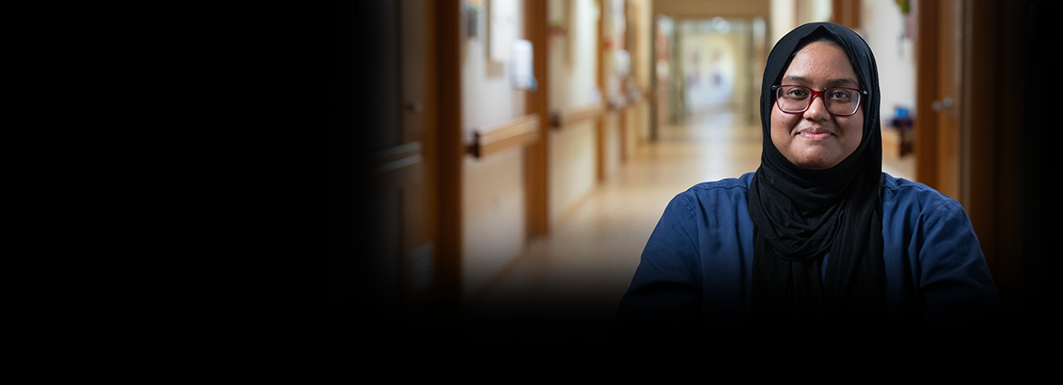 Person-centred outcome - Empowering Australians to look after their health and wellbeing and equipped with the right information and tools. Smiling female hospital staff member wearing hijab in dark blue uniform