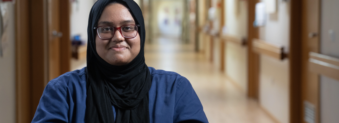 Person-centred outcome - Empowering Australians to look after their health and wellbeing and equipped with the right information and tools. Smiling female hospital staff member wearing hijab in dark blue uniform