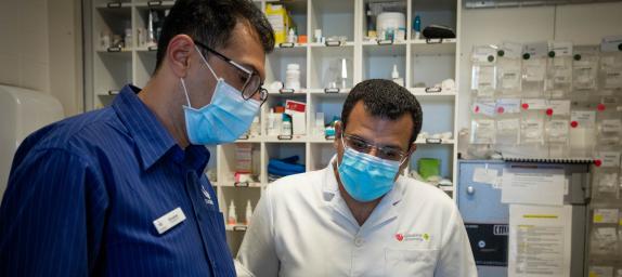 Two people wearing masks looking at a tablet