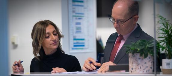 Two people looking at paperwork on a desk