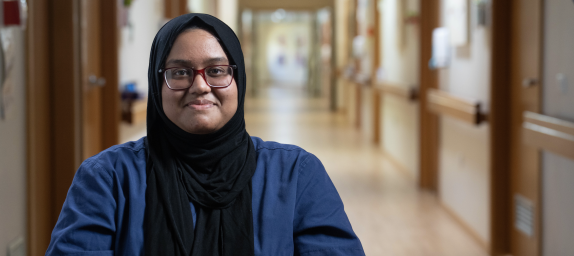 Person-centred outcome - Empowering Australians to look after their health and wellbeing and equipped with the right information and tools. Smiling female hospital staff member wearing hijab in dark blue uniform