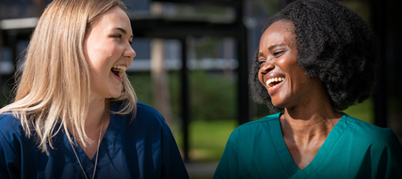 The Roadmap in Action is a curated collection of case studies which highlight the progress being made to advance digital health in Australia. Image contains two women laughing together, in green hospital uniforms, infront of a hospital.