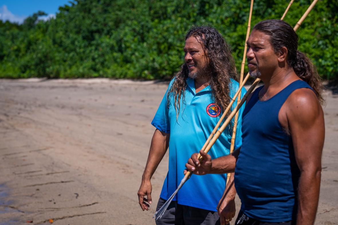 Photo: two Indigenous men with spears by the beach