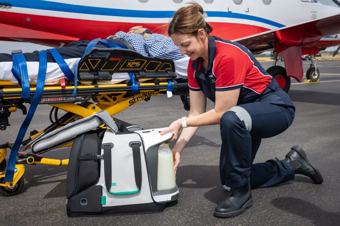 Person handling medical device next to a stretcher, by a medical plane.