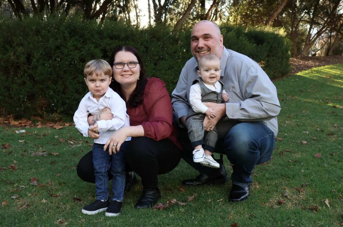 A mother, father and their two children sitting on the grass
